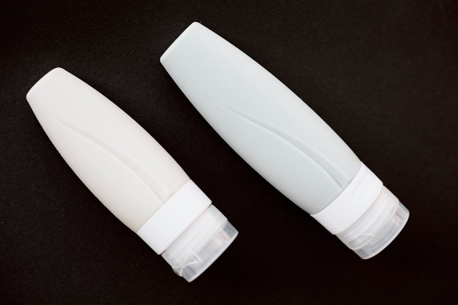 Two white skincare tubes placed on a black background, showcasing minimalist design.