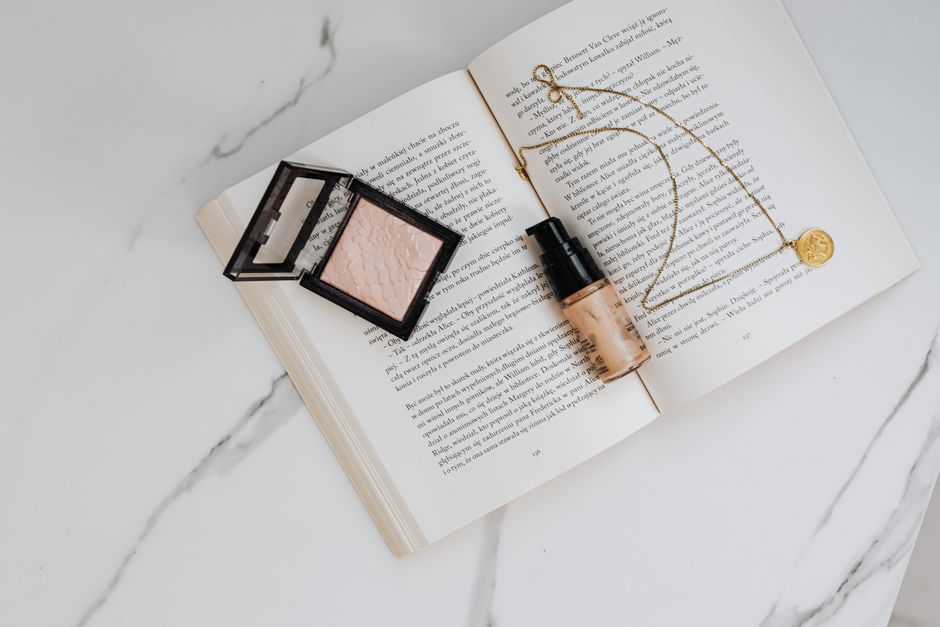 Elegant flat lay of beauty products and jewelry on an open book for a chic lifestyle aesthetic.