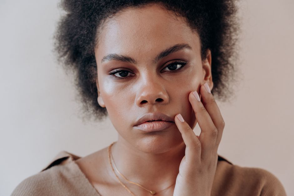 Close-up portrait of a woman with afro hair, expressing thoughtful introspection.
