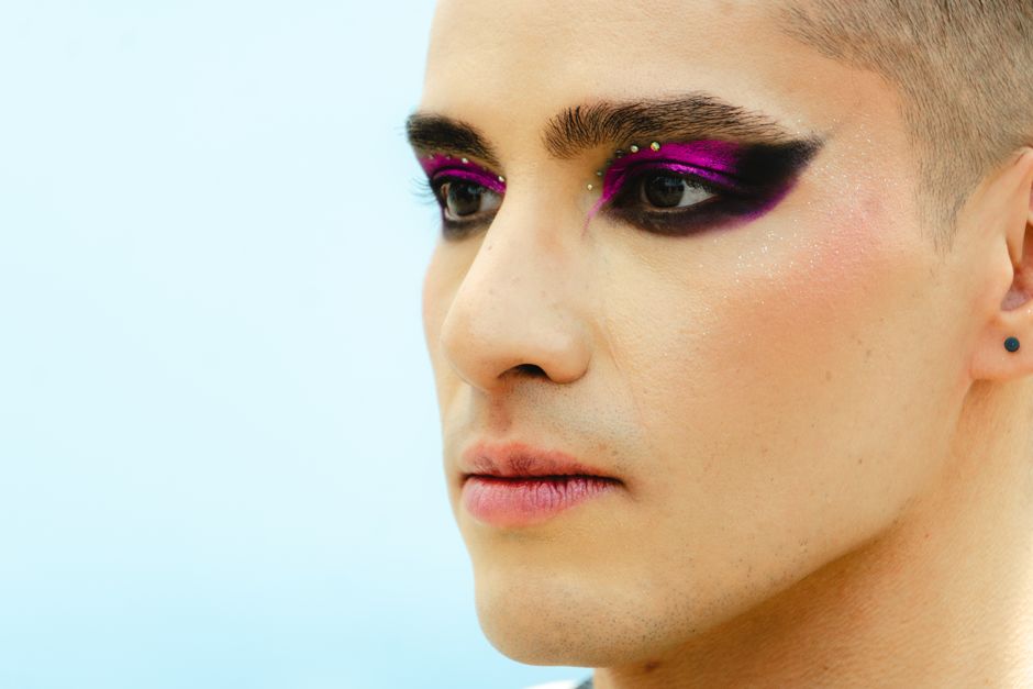Striking portrait of a man wearing bold, colorful eye makeup, showcasing style and individuality.