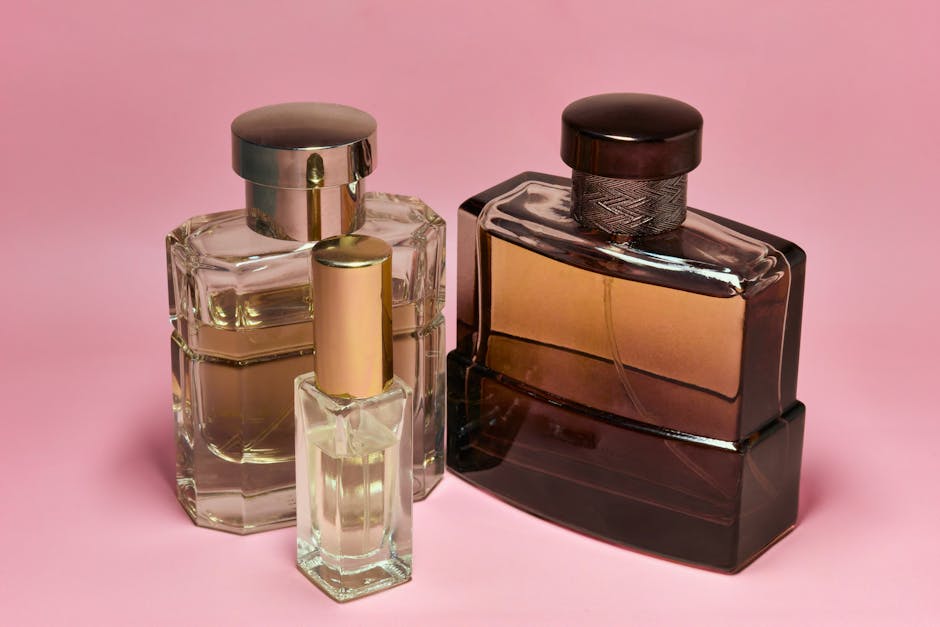 Three stylish perfume bottles with elegant caps on a pink backdrop, capturing a sense of luxury and sophistication.