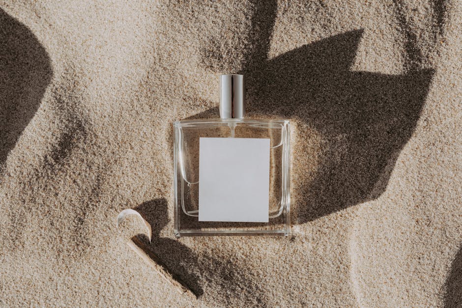 Elegant perfume bottle casting shadows on sand, ideal for beauty product concepts.