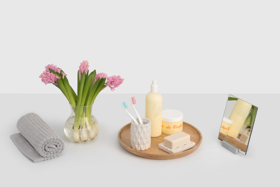 Modern vanity layout featuring pink hyacinths, toiletries, and a mirror on a wooden tray.