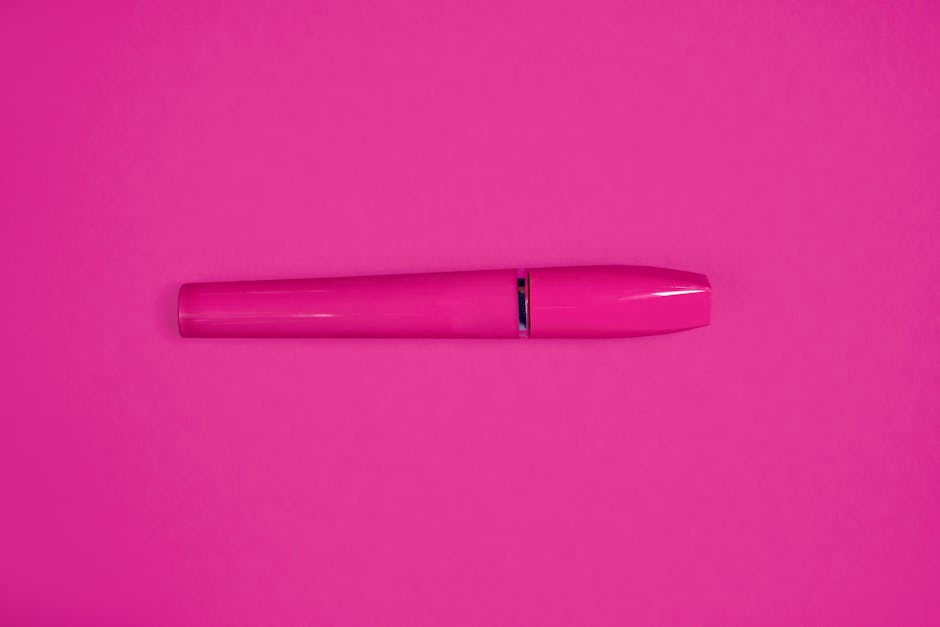 A bright pink mascara tube set against a matching pink background, perfect for beauty product marketing.