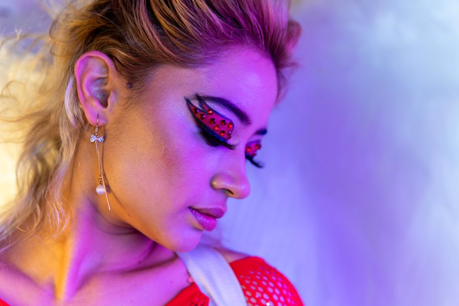 Close-up portrait showcasing vibrant makeup artistry with unique earring.