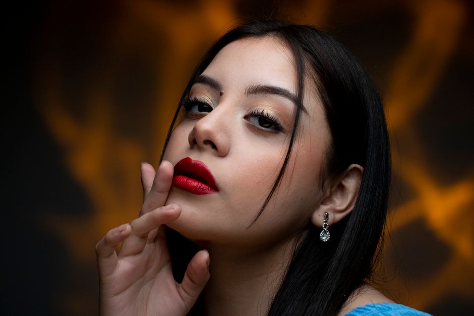 Close-up portrait of a woman with bold red lipstick and elegant earrings.