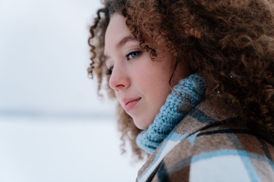 Close-up portrait of a woman wearing winter clothes and blue sweater outdoors.